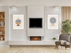 acantha aspire electric panormaic fire 50, in a chimney and with paintings either side and a chair on the right and a book shelf