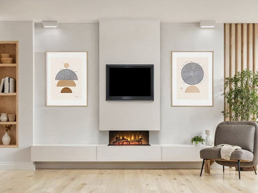 acantha aspire electric panormaic fire 50, in a chimney and with paintings either side and a chair on the right and a book shelf